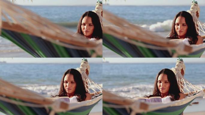 可爱的黑发女人在沙滩上的吊床上看书
