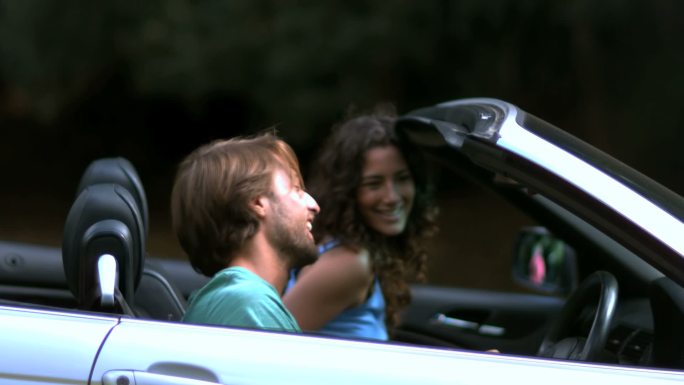 一个快乐的男人关上车门，而他的女朋友在自然中看着他