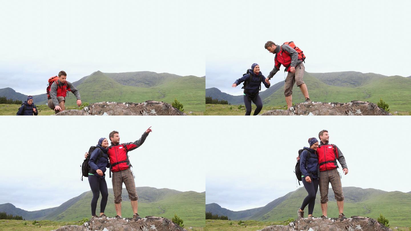 徒步旅行的夫妇到达了山顶，在乡间环顾四周
