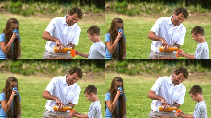 父亲在公园把橙汁倒进杯里特写