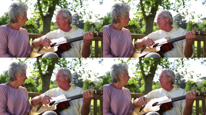 退休男子在公园里给他的妻子弹吉他特写