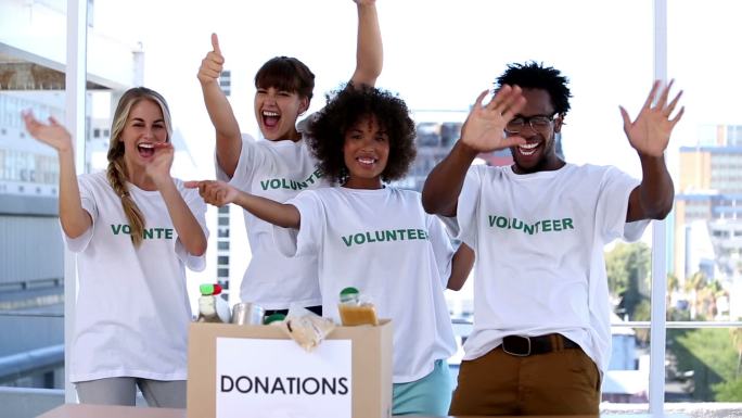 一群志愿者看着捐款箱里的食物欢呼特写