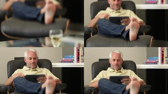 一个男人坐在客厅的躺椅上放松着他的平板电脑
