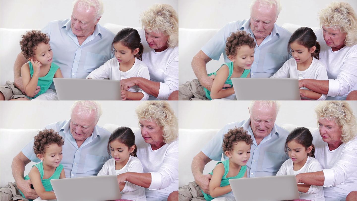 两个祖父母和两个孩子在沙发上用笔记本电脑