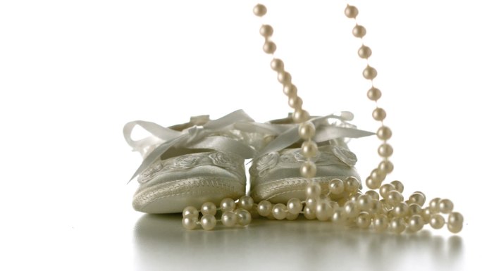 婴儿鞋子掉落在珍珠项链旁特写