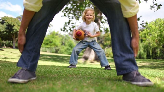 Father and son playing american football in a park