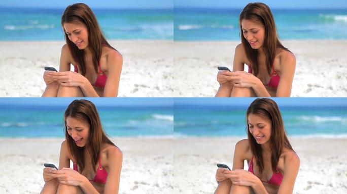 女人坐在沙滩上玩手机特写