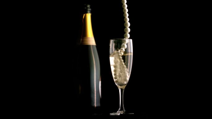 一串珍珠掉落在香槟杯里特写