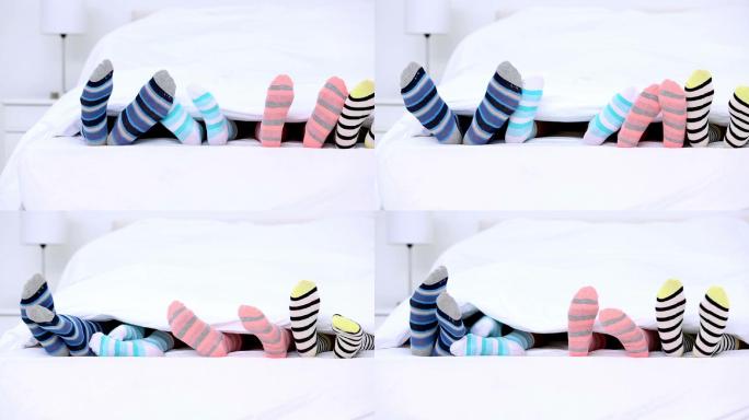 家人穿着条纹袜子的脚在床上踢被子