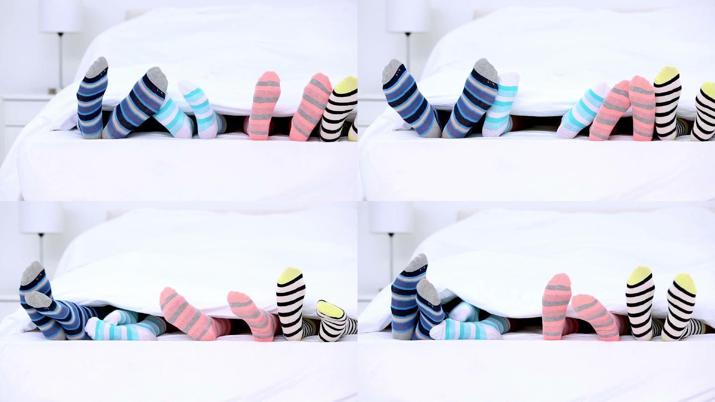 家人穿着条纹袜子的脚在床上踢被子
