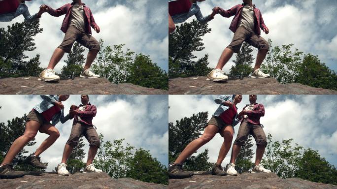 一个男人用慢动作扶着他的女朋友爬上一块石头