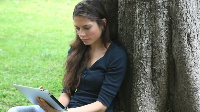 一名女子在公园里使用平板电脑的视频