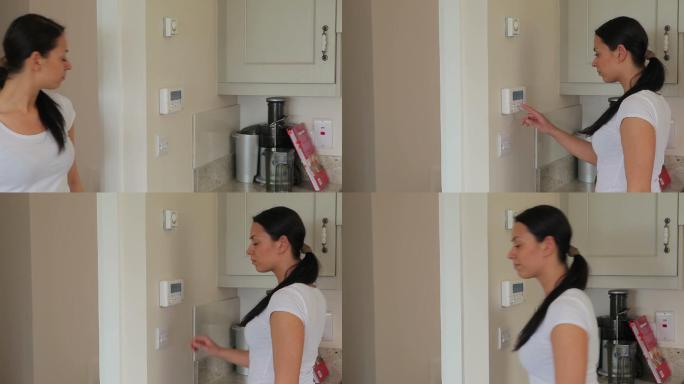 一名妇女打开厨房的家庭警报系统