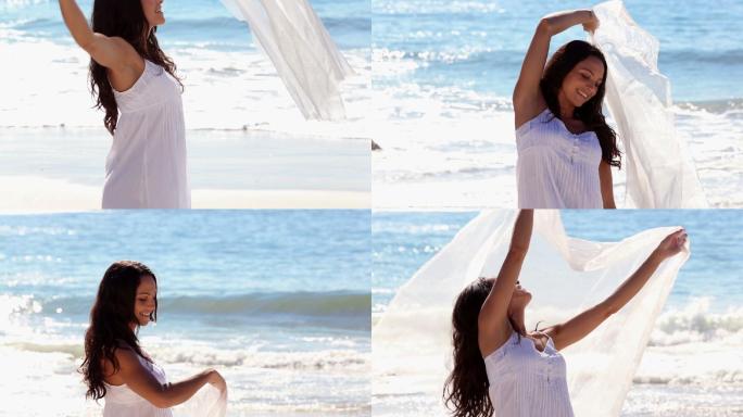 在阳光明媚的海滩上，美丽的女人围着围巾翩翩起舞