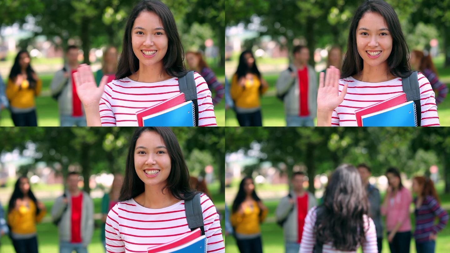 在校园里，一名学生对着镜头微笑挥手，身后是她的朋友