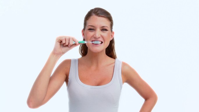 一个女人在白色的背景下用牙刷特写