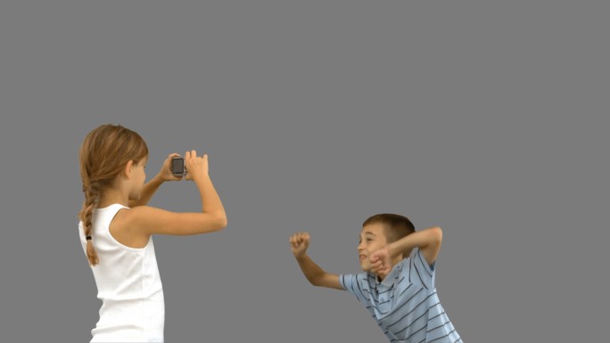 姐姐在灰色屏幕上用慢动作拍摄哥哥跳跃的照片