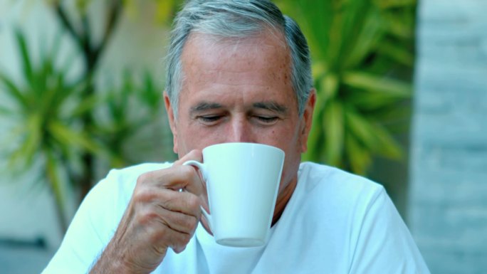 一个退休男子在外面慢镜头享受咖啡