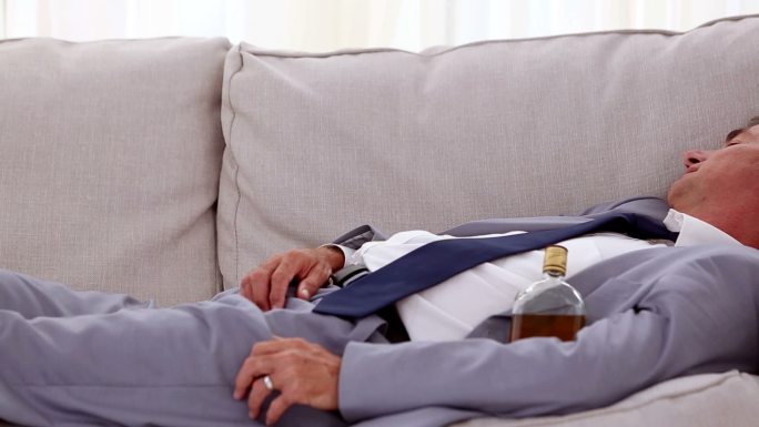酗酒的商人躺在等候室的沙发上睡觉