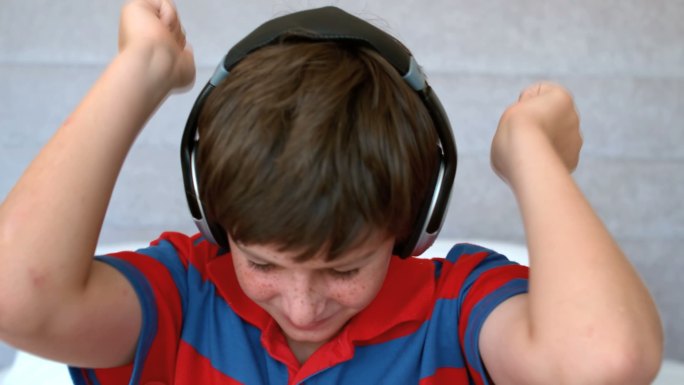 小男孩戴着耳机，以每秒500帧的慢动作欣赏音乐