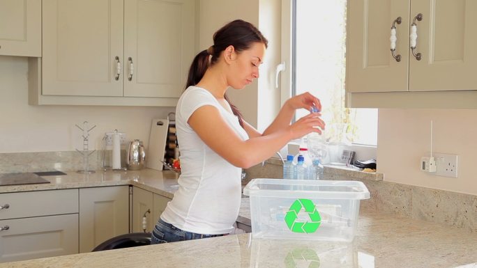 女人把塑料瓶倒入回收箱特写