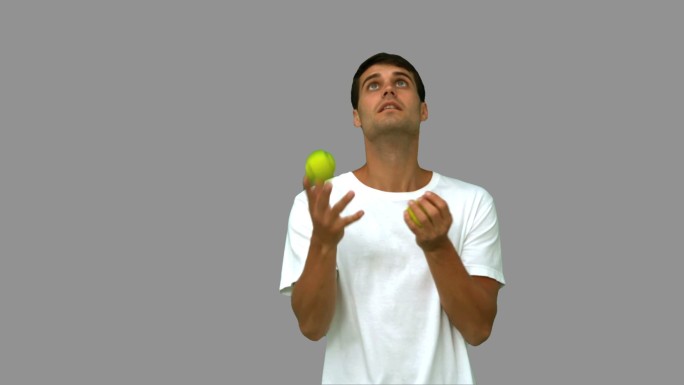男人在灰色背景下拿着网球向上抛特写