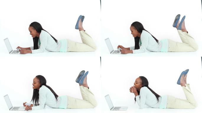 一个女人躺在地板上用笔记本电脑打字