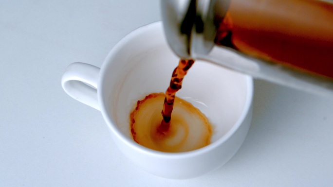 将咖啡从咖啡壶倒入白色杯子里特写