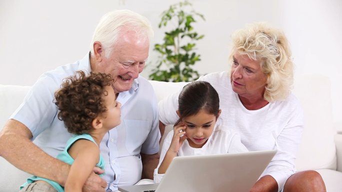 爷爷奶奶和他们的孙子在客厅里使用平板电脑