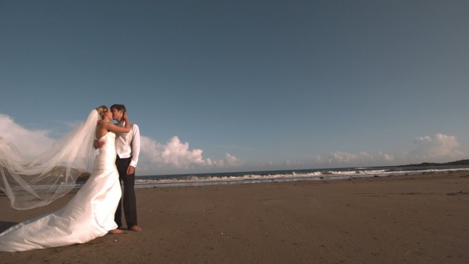 快乐的新婚夫妇在海滩上接吻的慢镜头