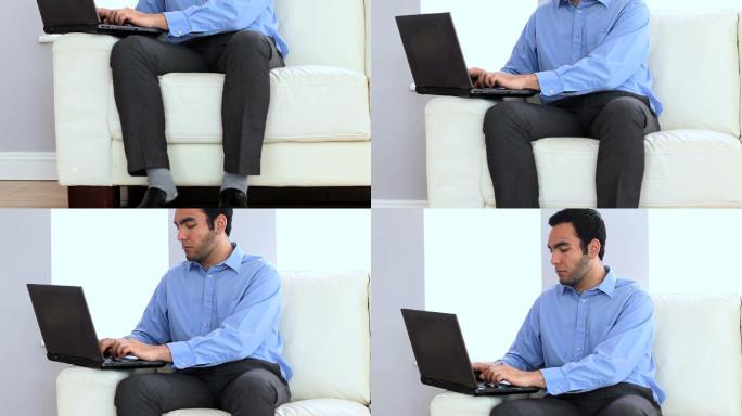 一个微笑的商人在沙发上使用笔记本电脑的肖像