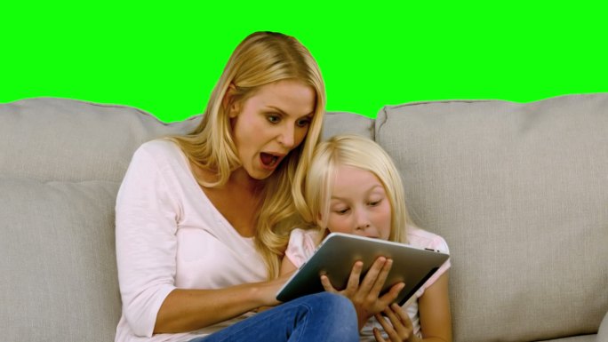 绿色背景下女人在沙发上给女孩读书特写