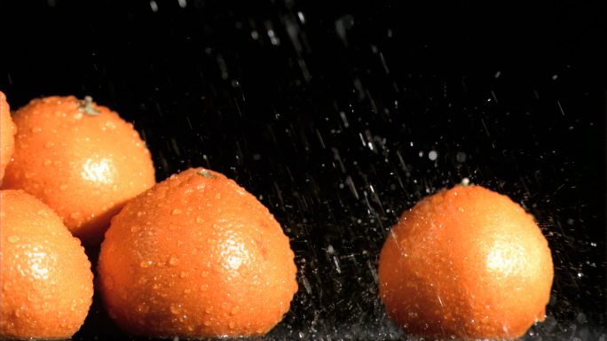 美味的橘子在超级慢镜头接受水在一个黑色的背景