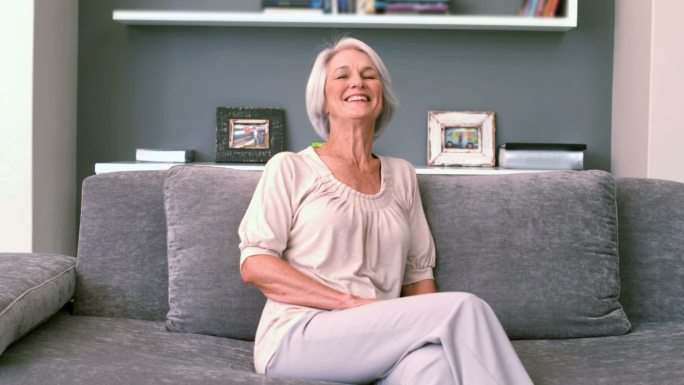 一个退休女人在沙发上慢动作地笑着