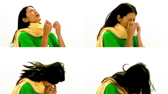 穿着绿色t恤和黄色围巾的亚洲女士在白色背景的慢镜头下打喷嚏