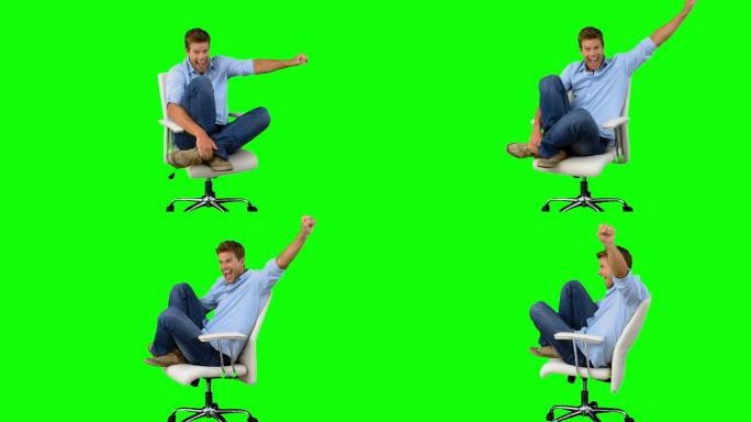 绿色背景下男人坐在椅子上举手欢呼特写