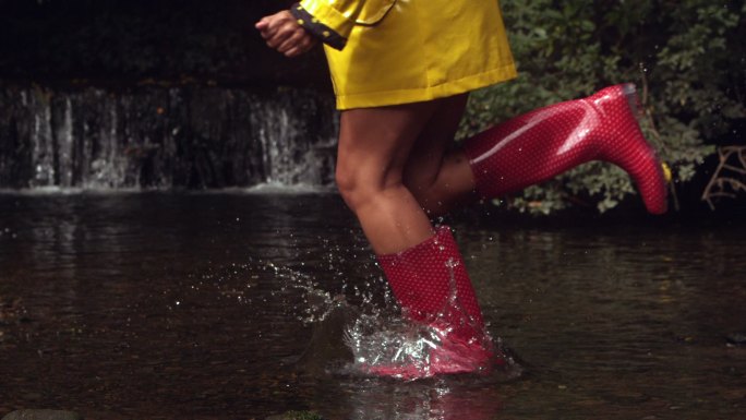 穿着粉色胶靴的女人在水里奔跑，溅起水花