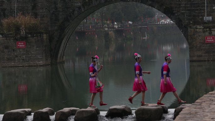 游客穿民族服装走在浦江上河壶源江石拱桥下