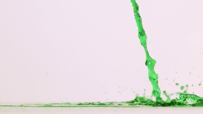 绿色液体以超慢的动作倒在白色背景的表面上