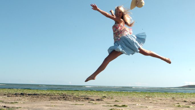 迷人的金发女郎在海滩上做芭蕾跳慢动作