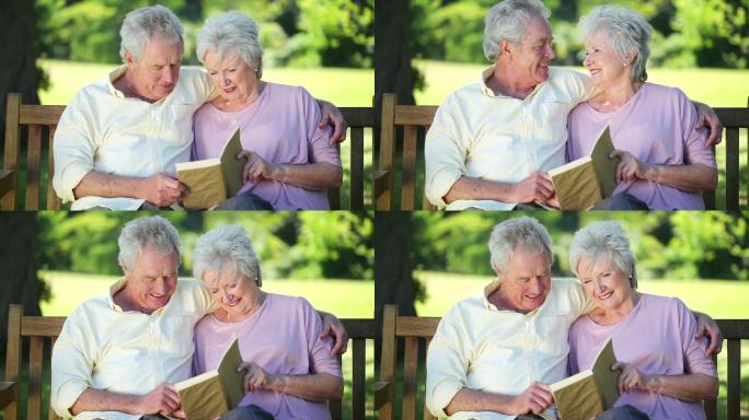 一对老夫妇坐在公园长椅上看书特写