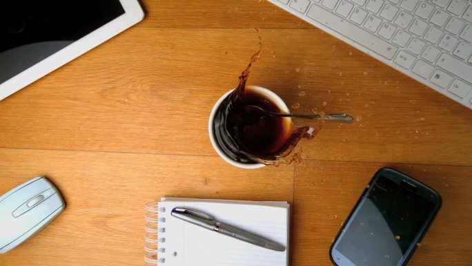 一茶匙的糖掉进一杯咖啡里，然后用平板电脑慢动作溅到办公桌上