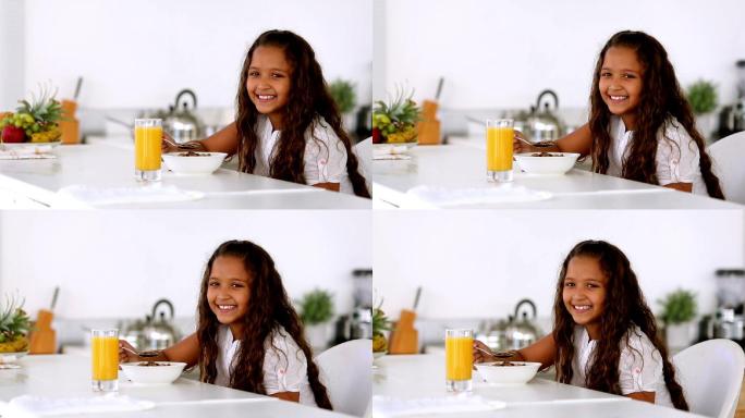小女孩在厨房吃早餐时对着镜头微笑