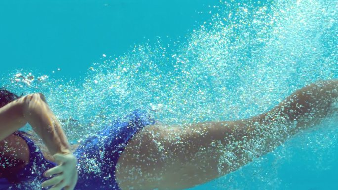 深色头发的女人在水下慢动作游泳