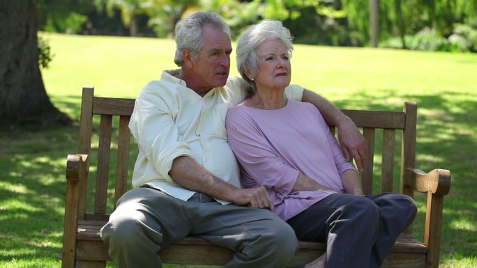 一对退休夫妇坐在公园的长椅上特写