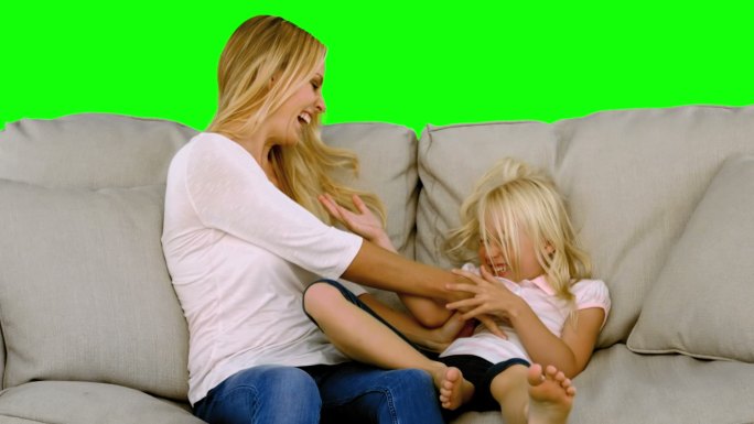 绿色屏幕下女儿和妈妈在沙发上玩耍特写