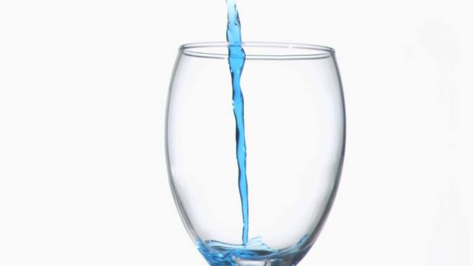 蓝色的涓涓细流以超慢的动作在白色的背景下流淌在酒杯里