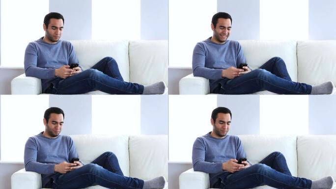 男人坐在沙发上用智能手机发短信
