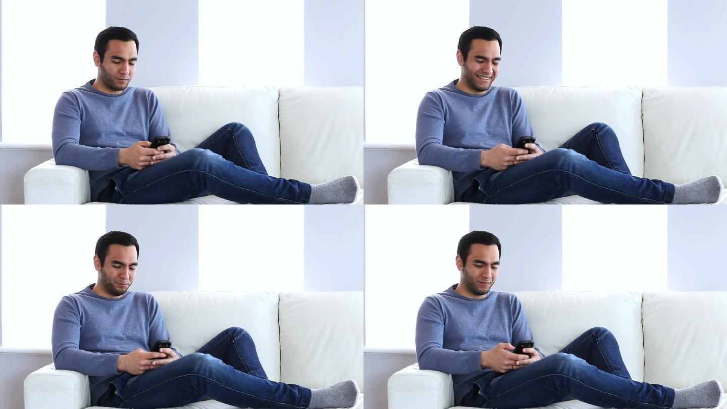 男人坐在沙发上用智能手机发短信