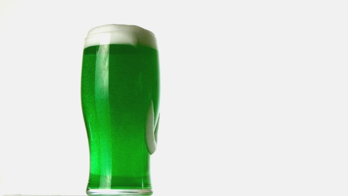 泡沫在一杯绿色啤酒上溢出特写